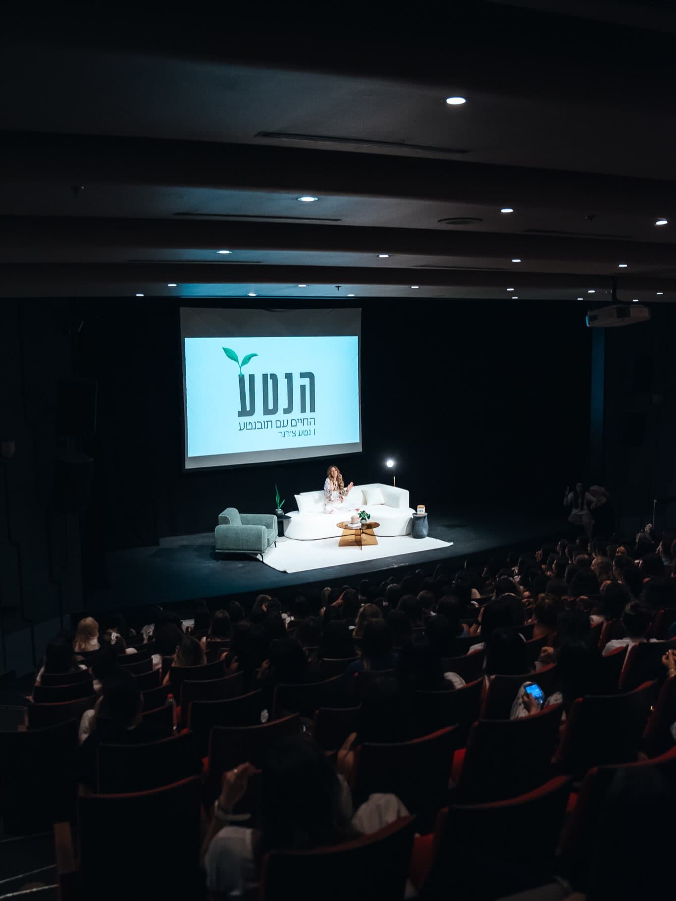 נטע מדברת מול אולם מלא במפגש חי